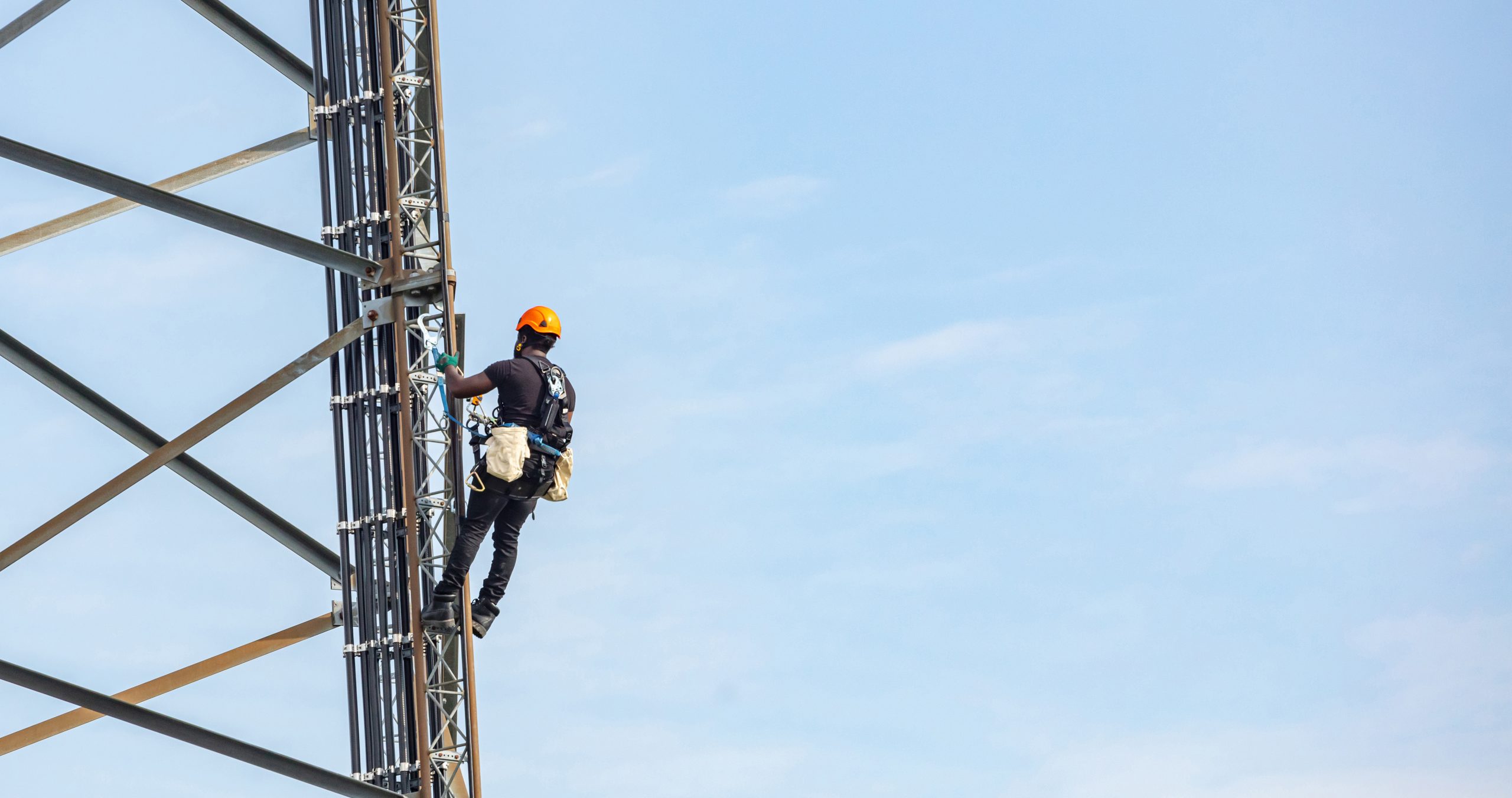 Telecom Infrastructure Axians technician climbing telecom tower blue background