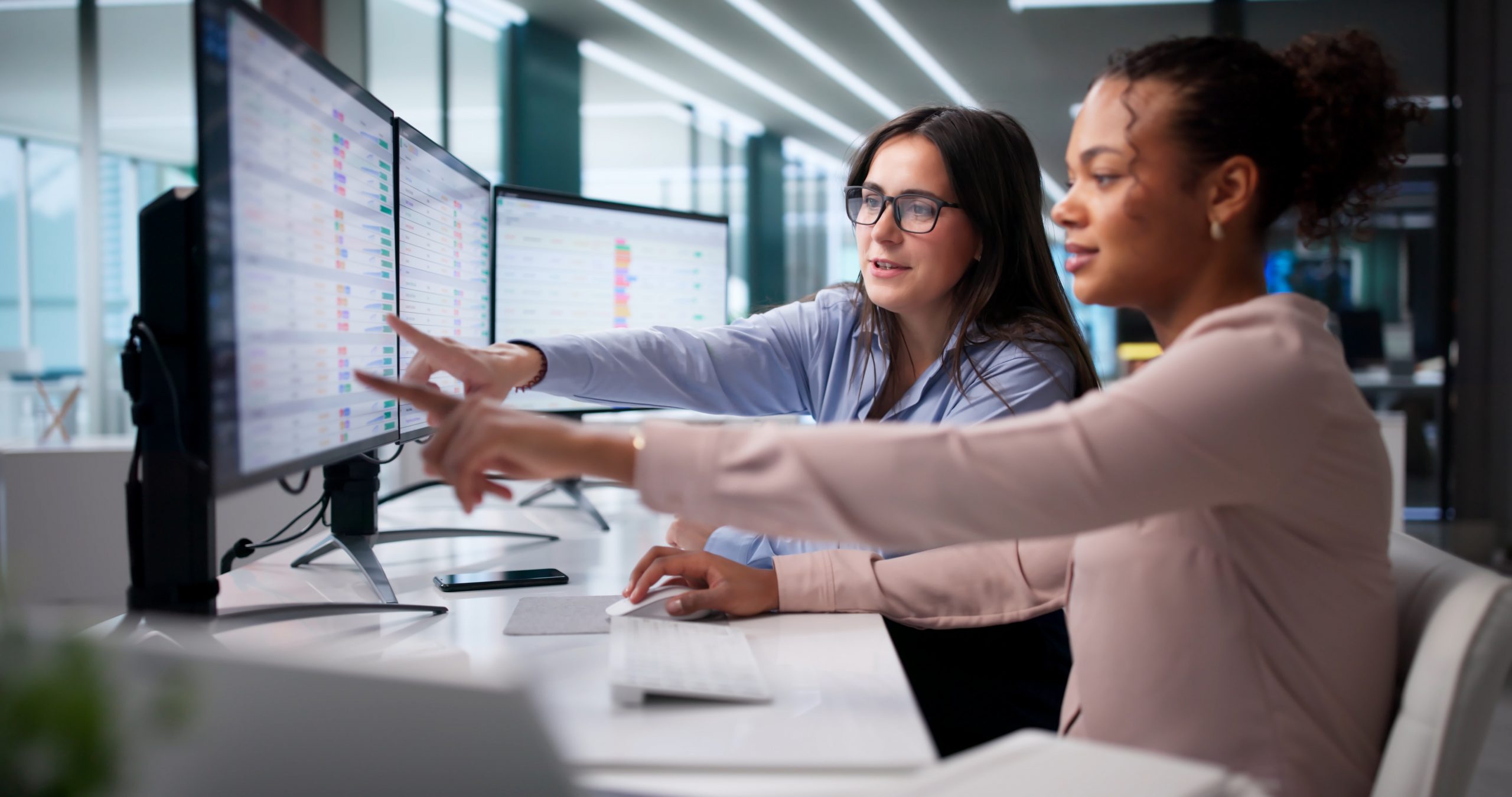 Team collaborating while analyzing AI data dashboards on a large monitor.