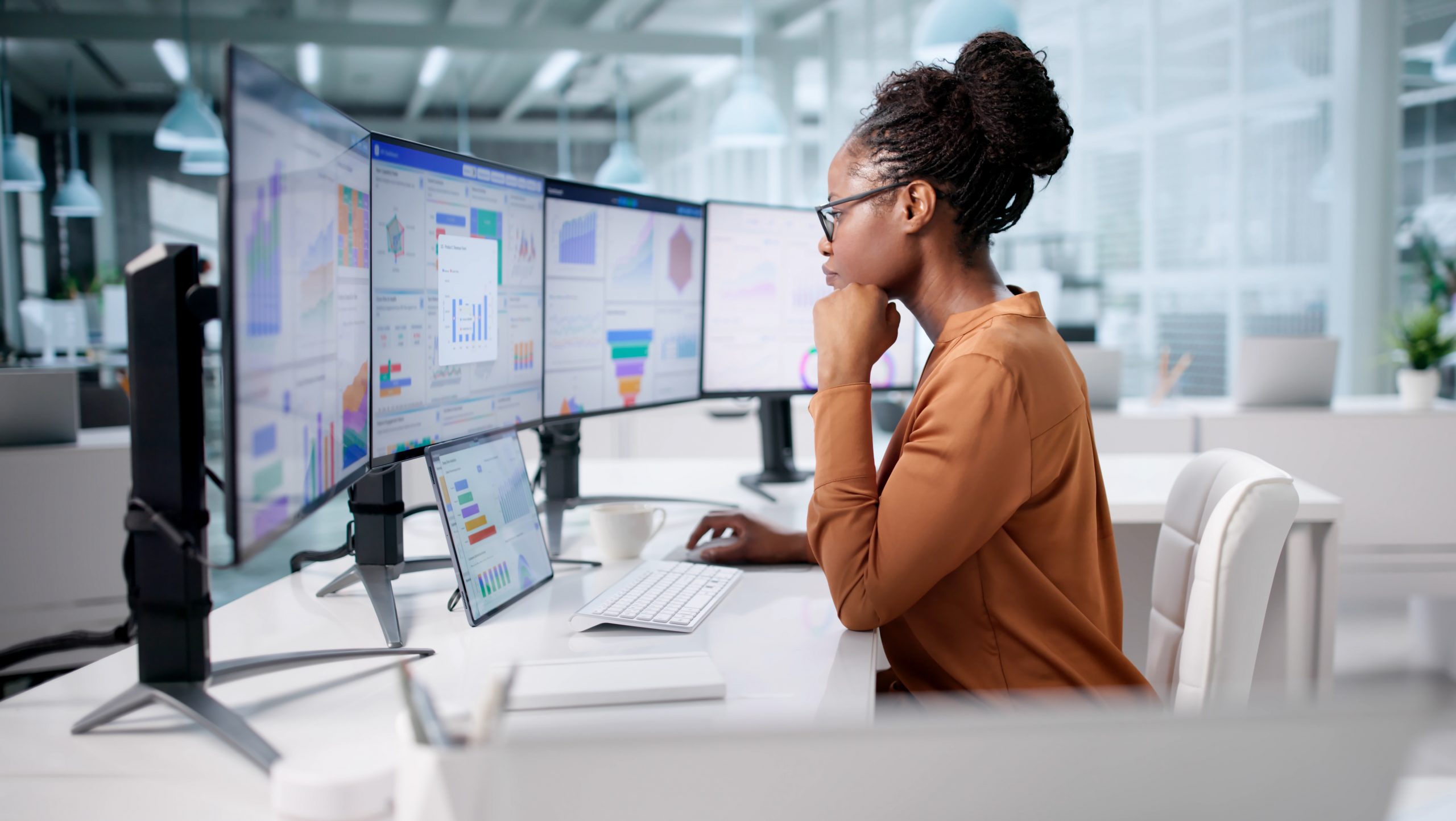 Business analyst reviewing enterprise planning dashboards across multiple monitors