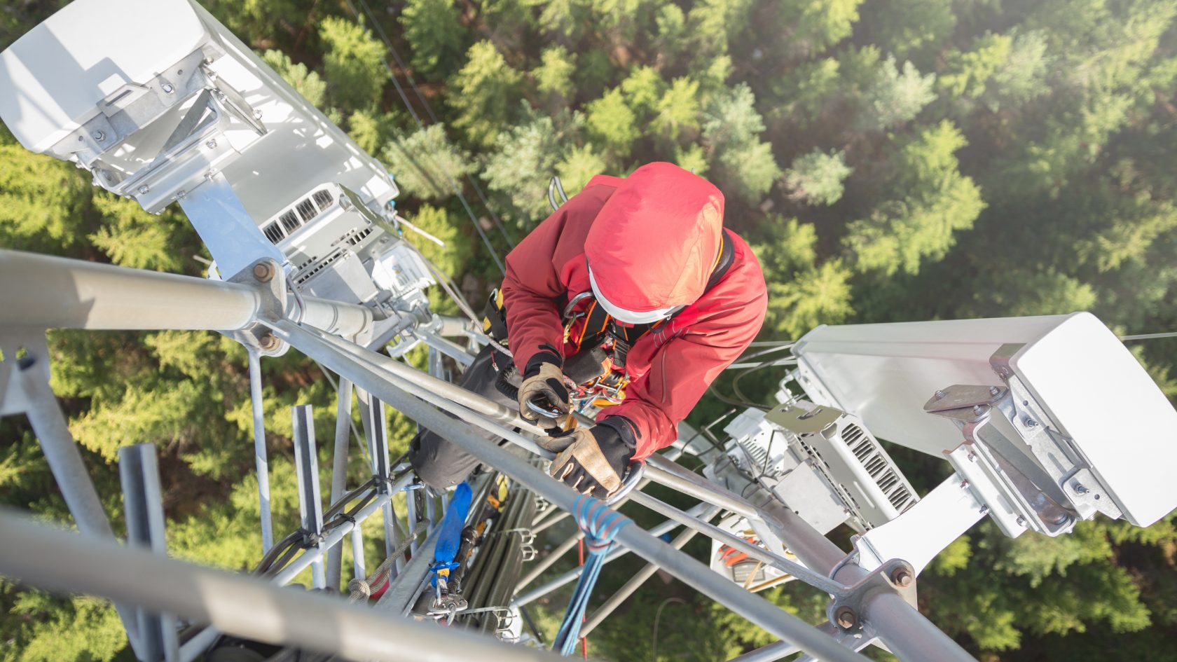 Technician installing wireless telecommunications equipment on a communications tower during network deployment.