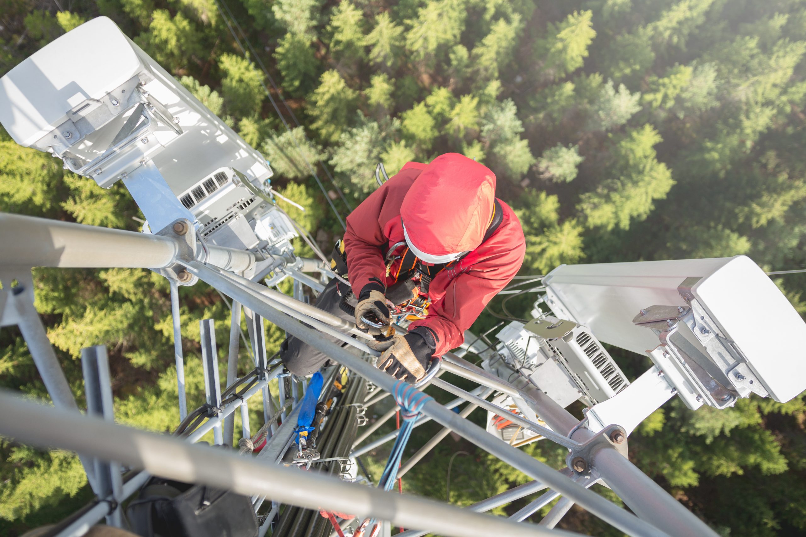 Technician installing wireless telecommunications equipment on a communications tower during network deployment.