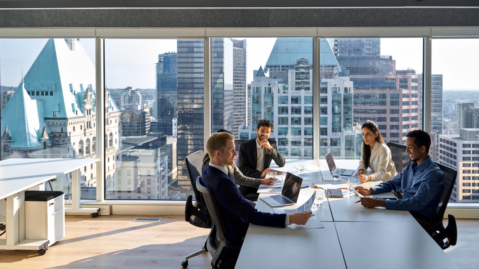 Executive team meeting in a modern office overlooking a city skyline.