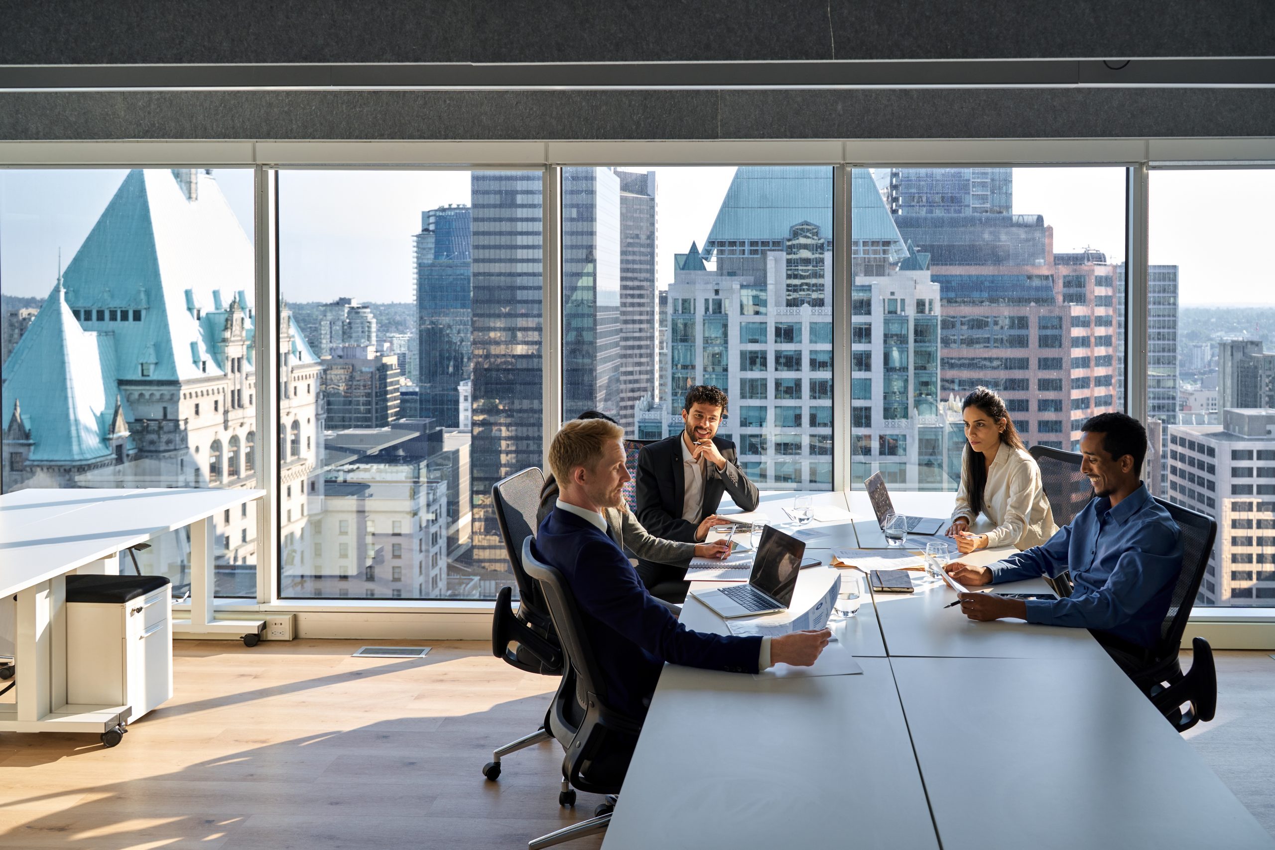 Executive team meeting in a modern office overlooking a city skyline.