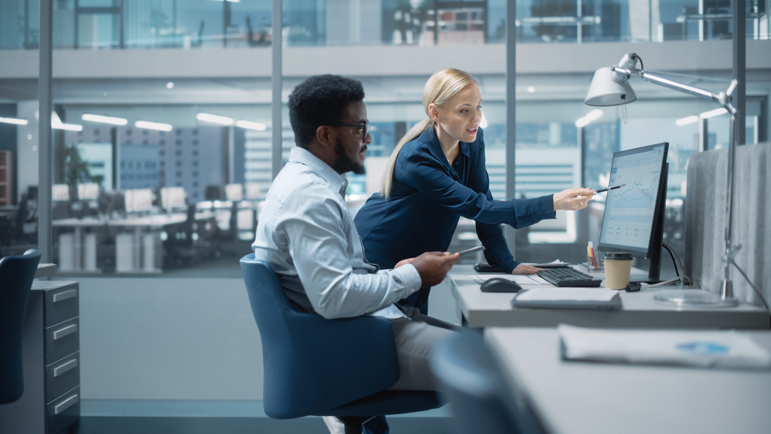 Two professionals reviewing analytics on a computer as part of a data and AI transformation project in the banking sector.