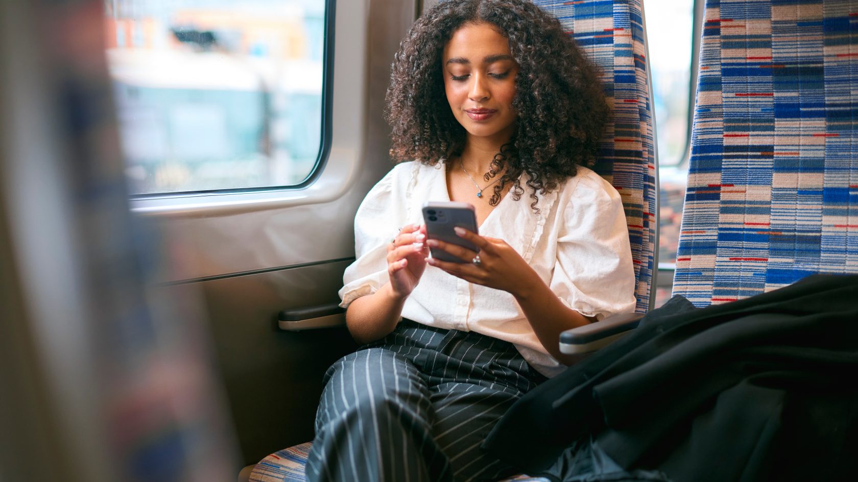 Train passenger using a smartphone while travelling, demonstrating connected digital services and modern rail travel.