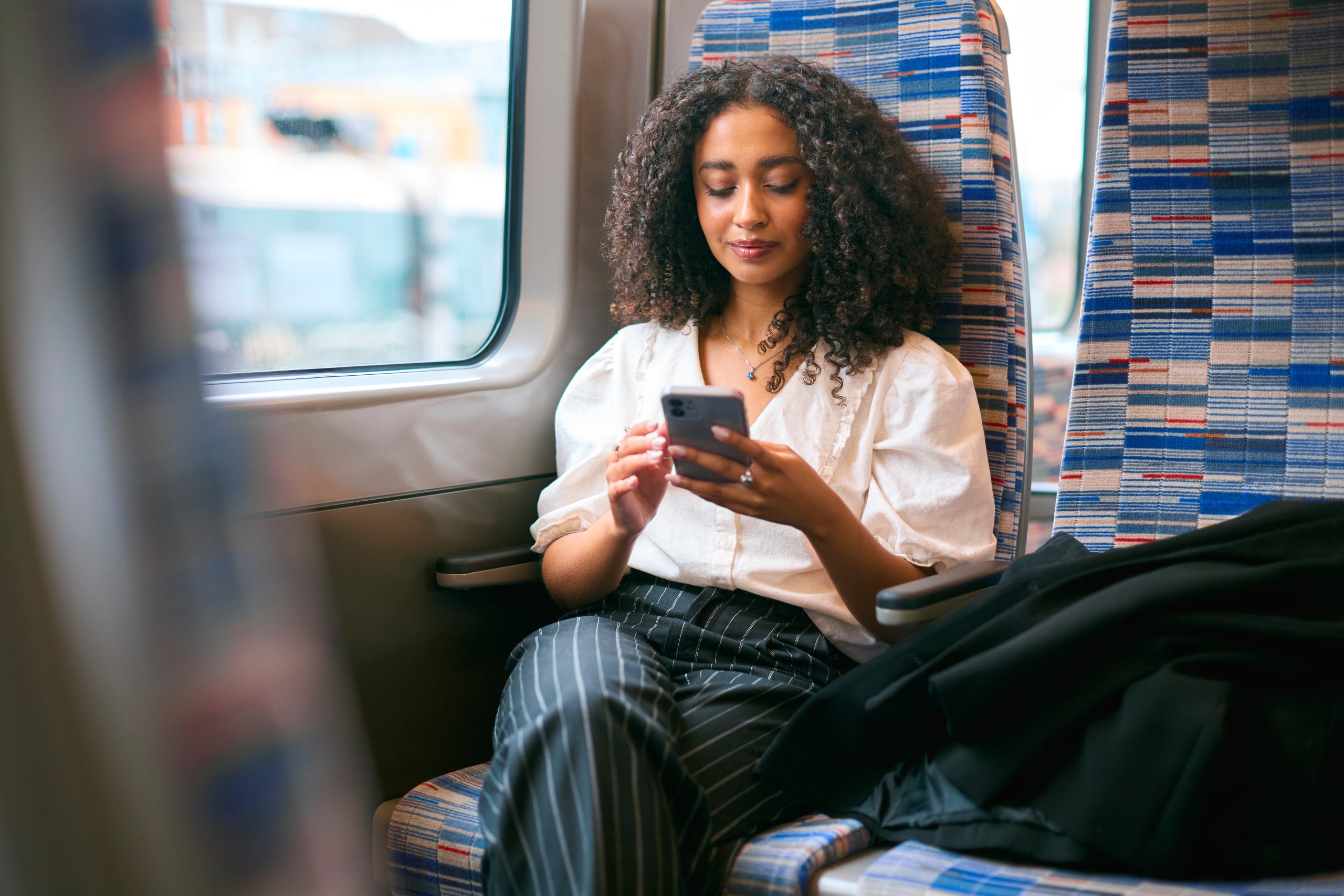 Train passenger using a smartphone while travelling, demonstrating connected digital services and modern rail travel.
